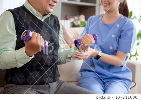 Asian caregiver woman or nurse training senior man lifting dumbbell for arm exercise. Asian caregiver woman or nurse training senior man lifting dumbbell for arm exercise. 107211000