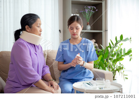Caregiver or nurse check neck of senior woman and explaining drug in living room. Caregiver or nurse check neck of senior woman and explaining drug in living room. 107211001
