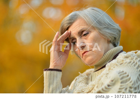Sad senior woman with headache in park 107211778