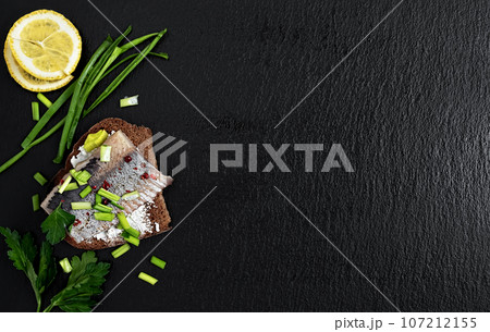 Herring sandwich (great appetizer for vodka) on the black background. Top view with copy space. Healthy sea food. Herring sandwich (great appetizer for vodka) on the black background. Top view with copy space. Healthy sea food. 107212155