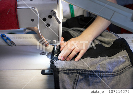 hands of a seamstress working for the machine .close up hands of a seamstress working for the machine .close up 107214373