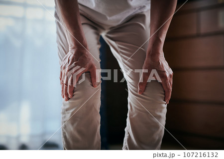 両膝が痛くて手で押さえるシニア女性 両膝が痛くて手で押さえるシニア女性 107216132