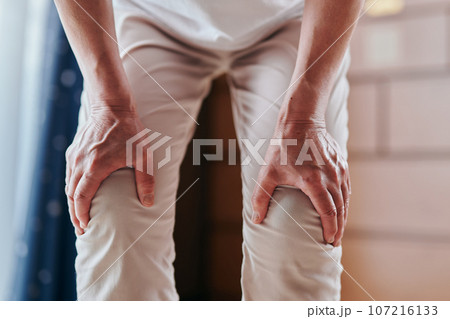 両膝が痛くて手で押さえるシニア女性 両膝が痛くて手で押さえるシニア女性 107216133