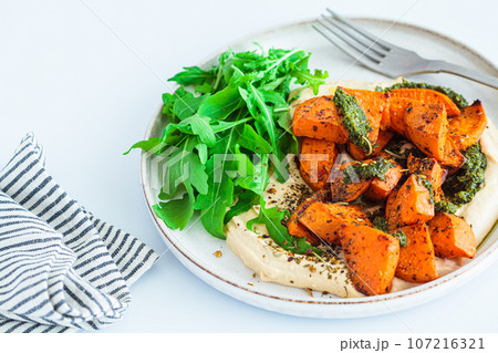 Vegan lunch - hummus, baked sweet potato and pesto, white background. 107216321
