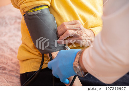 A doctor using a sphygmomanometer with a stethoscope revealed arterial hypertension in a patient in the hospital. A doctor using a sphygmomanometer with a stethoscope revealed arterial hypertension in a patient in the hospital. 107216997