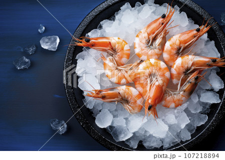 Fresh shrimp with ice in bowl on blue wooden table 107218894