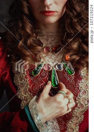 Closeup on medieval queen in red dress with jewellery 107219224
