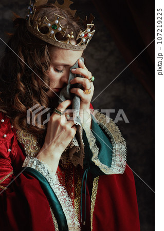unhappy medieval queen in red dress with handkerchief crying 107219225