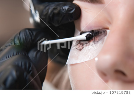 Eyelash procedure with master and client in a beauty salon. close-up of a model's eye, eyelash tinting process 107219782