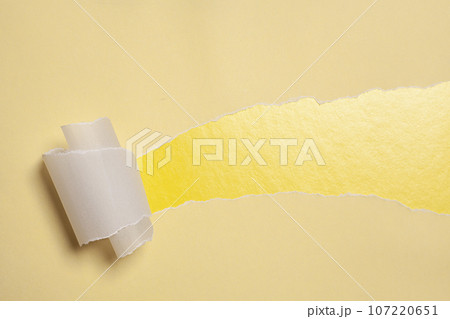 Torn paper with opening showing yellow background. 107220651
