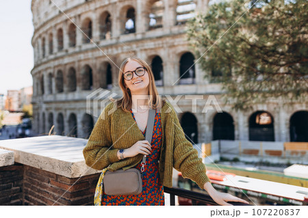 A happy blond woman tourist is standing near the Coliseum, old ruins at the center of Rome, Italy. Concept of traveling famous landmarks. Girl is walking on a sunny day A happy blond woman tourist is standing near the Coliseum, old ruins at the center of Rome, Italy. Concept of traveling famous landmarks. Girl is walking on a sunny day 107220837
