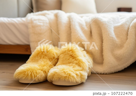 warm, fuzzy slippers next to a bed 107222470