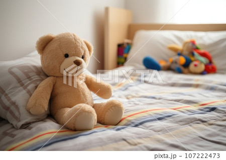 a stuffed animal sitting on the corner of a childs bed 107222473