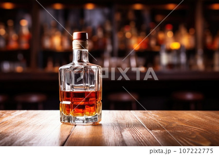 a solo half-empty whiskey bottle on a wooden counter 107222775