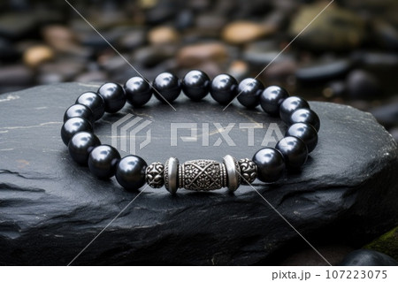 a single pearl beaded bracelet elegantly placed on a slate stone 107223075