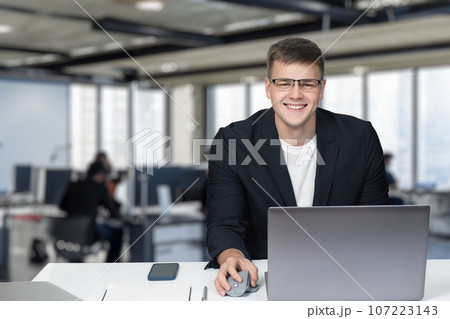 The businessman is smiling at his workplace at the table. 107223143