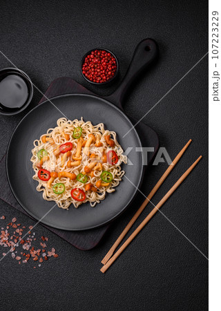 Delicious Asian cuisine dish with rice noodles, peppers, mushrooms and spices Delicious Asian cuisine dish with rice noodles, peppers, mushrooms and spices 107223229