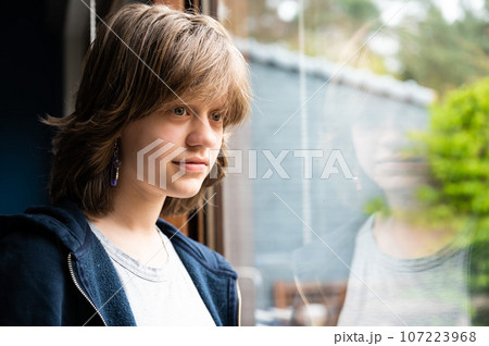 Portrait of a dreaming 15 year old girl looking through the window, Belgium Portrait of a dreaming 15 year old girl looking through the window, Belgium 107223968