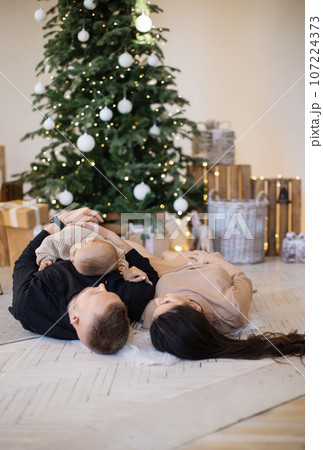 Mother, father and daughter lying on floor at decorated home 107224373
