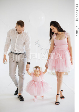 Parents holding hands with little girl in festive studio 107224733