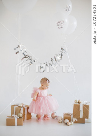 Lovely little girl celebrating birthday in decorated studio Lovely little girl celebrating birthday in decorated studio 107224801