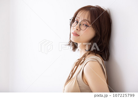 白壁に寄りかかるメガネをかけた女子大生 白壁に寄りかかるメガネをかけた女子大生 107225799