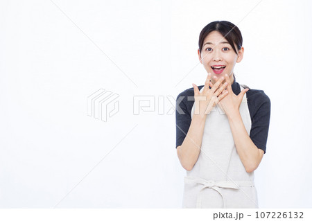 白い背景の前で笑顔でおどろく30代の主婦 白い背景の前で笑顔でおどろく30代の主婦 107226132