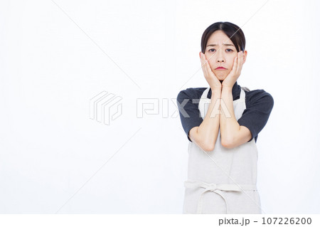 白い背景の前で真剣に悩んでいる30代の主婦 107226200
