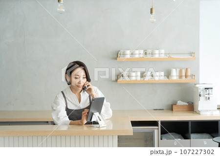 カフェで電話を受けるスタッフ カフェで電話を受けるスタッフ 107227302