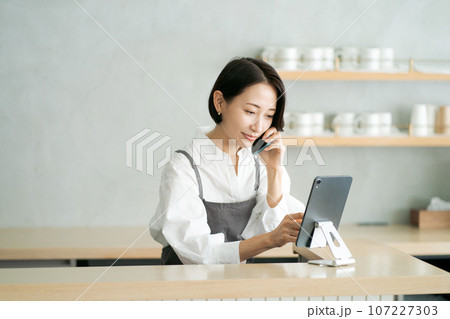 カフェで電話を受けるスタッフ カフェで電話を受けるスタッフ 107227303