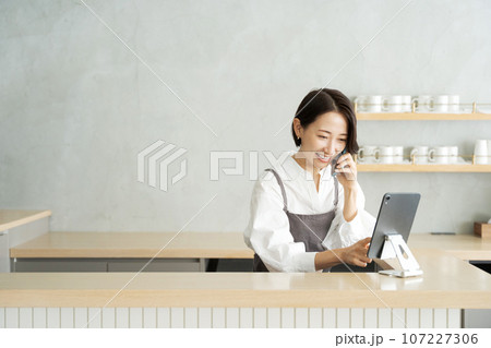 カフェで電話を受けるスタッフ カフェで電話を受けるスタッフ 107227306