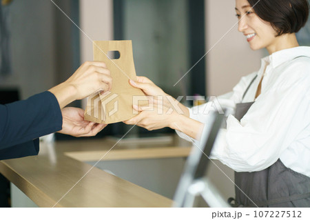 商品を受け渡すカフェ店員と客 107227512