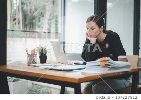 Overworked businesswoman suffering from headache and thinking how to end work. Overworked businesswoman suffering from headache and thinking how to end work. 107227812
