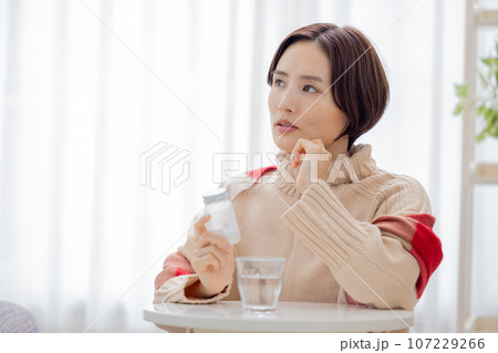 体調不良 薬の瓶を見る女性 体調不良 薬の瓶を見る女性 107229266