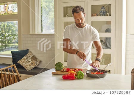 Man cutting vegetables in kitchen 107229397