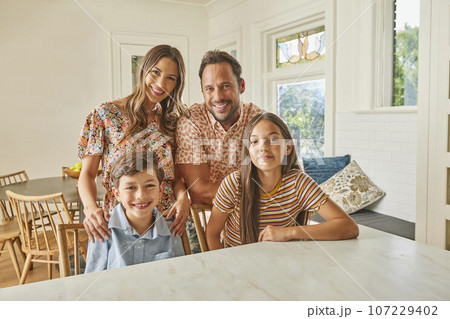 Portrait of smiling family with two children (8-9, 12-13) in kitchen 107229402