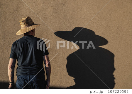 Man in hat casting shadow on wall 107229595