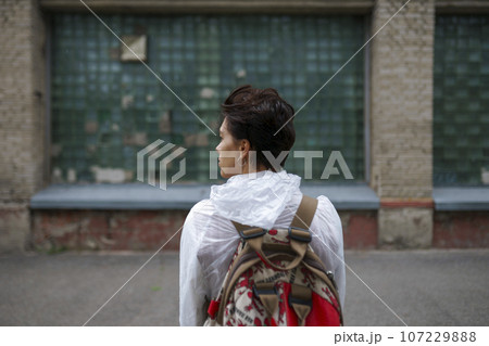 Rear view of young woman looking away while standing with backpack in city 107229888