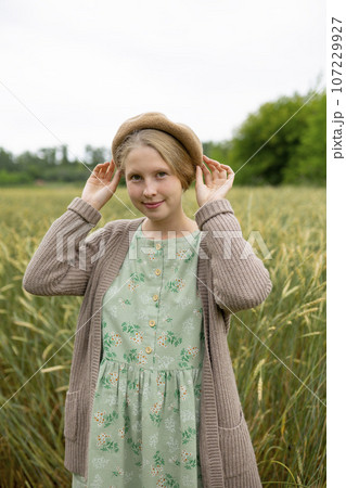 Portrait of young woman wearing beret standing in wheat field 107229927