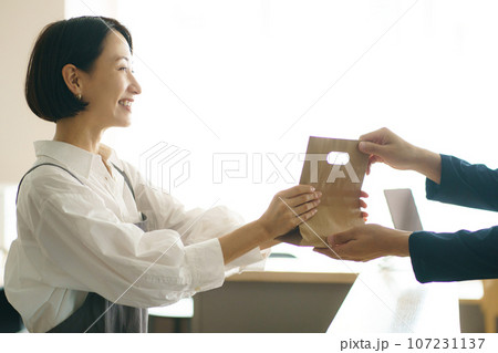 紙袋を渡す40代女性 紙袋を渡す40代女性 107231137