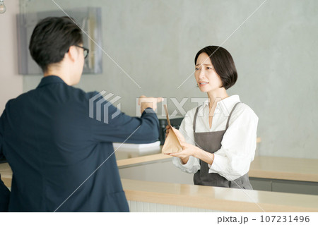 紙袋を受け渡す女性店員 紙袋を受け渡す女性店員 107231496