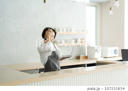 カフェで頭を抱える女性従業員 カフェで頭を抱える女性従業員 107231654