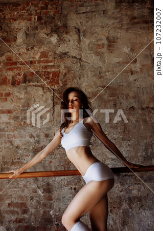 Beautiful sportswoman on the background of a brick wall Beautiful sportswoman on the background of a brick wall 107232007