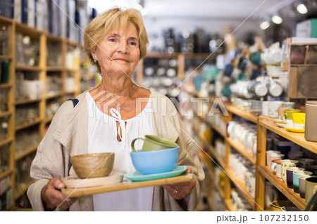 Mature woman choosing new dishes at store Mature woman choosing new dishes at store 107232150
