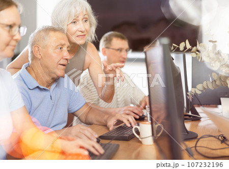 Senior man attending computer class under guidance of aged female teacher Senior man attending computer class under guidance of aged female teacher 107232196
