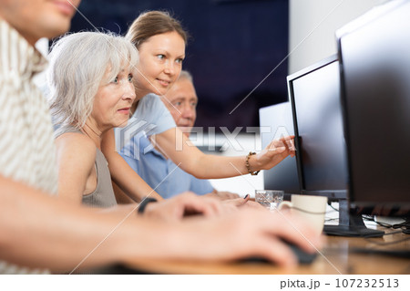 Female teacher helps an elderly woman learn how to use computer in nursing home 107232513