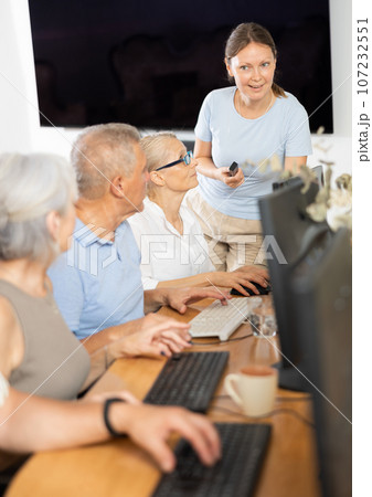 Woman teacher teaching elderly people how to use computer Woman teacher teaching elderly people how to use computer 107232551