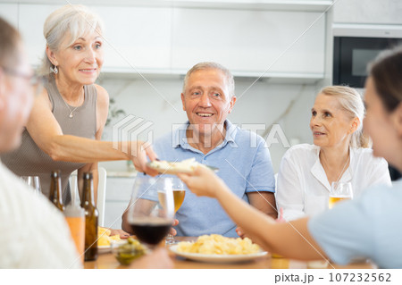 Old men and women talking merrily while having snack in the kitchen 107232562