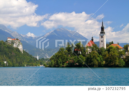 南欧スロヴェニアのブレッド湖　湖面に浮かぶブレッド島の聖母被昇天教会とブレッド城とユリアンアルプス 107232795