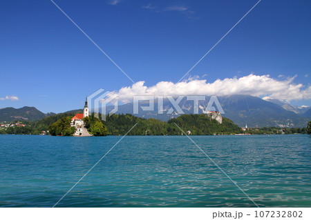 南欧スロヴェニアのブレッド湖　湖面に浮かぶブレッド島の聖母被昇天教会とブレッド城とユリアンアルプス 107232802